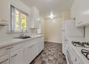 Thumbnail 3 of 29 - A kitchen with white cabinets and a tiled floor.