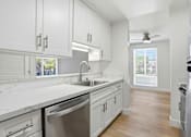 Thumbnail 76 of 92 - A kitchen with white cabinets and a stainless steel dishwasher.