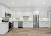 Thumbnail 61 of 67 - A modern kitchen with white cabinets and stainless steel appliances.