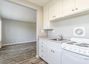 Thumbnail 32 of 42 - A kitchen with white appliances and cabinets.