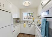 Thumbnail 16 of 33 - A white kitchen with a refrigerator on the left and a microwave on the right.