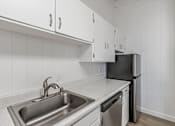 Thumbnail 36 of 44 - A kitchen with a black fridge and a stainless steel sink.