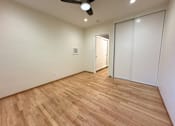 Thumbnail 21 of 33 - A room with a ceiling fan and wooden flooring.