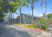 Thumbnail 1 of 31 - A building with a driveway and trees in front.