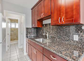 Thumbnail 17 of 38 - A kitchen with brown cabinets and a granite countertop.