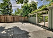 Thumbnail 11 of 27 - A backyard with a wooden fence and a covered patio area.
