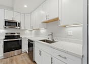 Thumbnail 62 of 67 - A modern kitchen with white cabinets and stainless steel appliances.