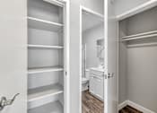 Thumbnail 38 of 40 - A white closet with shelves and a bathroom in the background.