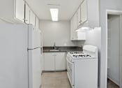 Thumbnail 45 of 55 - A white kitchen with a refrigerator, stove, and sink.