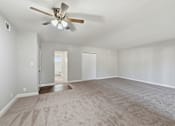 Thumbnail 31 of 33 - A room with a ceiling fan and carpeted floor.