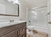 Thumbnail 28 of 52 - A bathroom with a white sink, a toilet, and a walk-in shower.