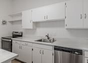 Thumbnail 24 of 44 - A kitchen with white cabinets and a stainless steel dishwasher.