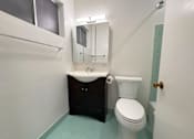 Thumbnail 15 of 33 - A white toilet sits next to a sink in a small bathroom.