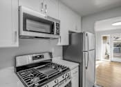 Thumbnail 2 of 31 - A modern kitchen with a black stove top oven and a black refrigerator.