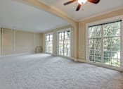 Thumbnail 33 of 42 - A spacious room with a ceiling fan and large windows.