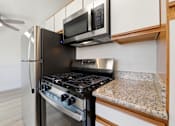 Thumbnail 62 of 63 - A modern kitchen with a black stove and microwave above it.