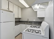 Thumbnail 48 of 55 - A white kitchen with a stove and cabinets.