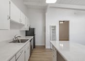 Thumbnail 40 of 44 - A kitchen with white cabinets and a black refrigerator.