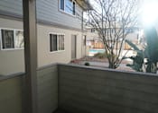 Thumbnail 14 of 22 - A balcony with a view of a building and trees.