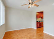 Thumbnail 24 of 37 - A room with a ceiling fan and wooden floors.