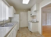Thumbnail 22 of 37 - A kitchen with white cabinets and a tiled floor.