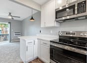 Thumbnail 26 of 53 - a kitchen with white cabinets and black appliances