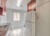 Thumbnail 21 of 38 - A white refrigerator in a kitchen with brown cabinets.