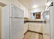 Thumbnail 42 of 43 - A white refrigerator stands in a kitchen with white cabinets and a tiled floor.