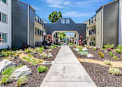 Thumbnail 26 of 41 - A concrete pathway leads through a landscaped courtyard between two buildings.
