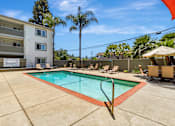 Thumbnail 23 of 43 - A swimming pool surrounded by a concrete floor and chairs.
