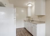 Thumbnail 26 of 37 - A white kitchen with a sink and cabinets.