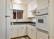 Thumbnail 43 of 43 - A white kitchen with a refrigerator, oven, and sink.