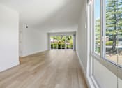 Thumbnail 69 of 92 - A room with wooden floors and a view of trees through the window.