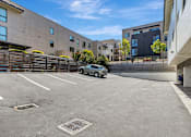 Thumbnail 34 of 43 - A parking lot with a car parked in the middle and buildings in the background.