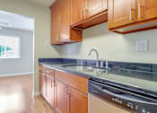 Thumbnail 22 of 37 - A kitchen with wooden cabinets and a black dishwasher.