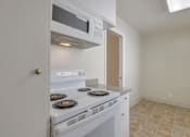 Thumbnail 21 of 37 - A white kitchen with a stove and microwave built into the cabinetry.