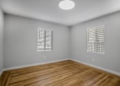 Thumbnail 10 of 31 - A room with wooden floors and two windows with blinds.