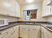 Thumbnail 24 of 43 - A kitchen with white cabinets and a black countertop.
