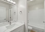 Thumbnail 53 of 92 - A white bathroom with a sink, mirror, toilet and bathtub.