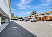 Thumbnail 33 of 43 - A parking lot with cars parked and a building on the left.