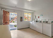 Thumbnail 7 of 13 - a laundry room with four washers and dryers and a door to a house
