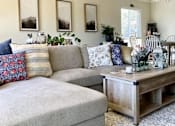 Thumbnail 22 of 22 - A living room with a grey couch, a wooden coffee table, and a ceiling fan.