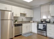 Thumbnail 13 of 35 - A modern kitchen with a stainless steel refrigerator and oven.