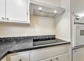 Thumbnail 30 of 43 - A kitchen with white cabinets and a marble countertop.