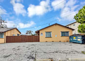 Thumbnail 5 of 38 - A yellow house with a brown fence and a blue dumpster in front.