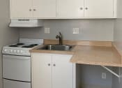 Thumbnail 2 of 10 - a kitchen with white cabinets and a stove and sink