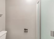 Thumbnail 31 of 42 - A white toilet in a small bathroom with a glass door.