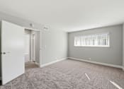 Thumbnail 14 of 33 - A room with a carpeted floor and a window with blinds.