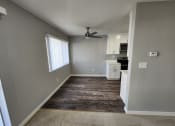Thumbnail 6 of 16 - an empty living room with a ceiling fan and a kitchen