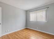 Thumbnail 27 of 38 - A room with wooden floors and a window with blinds.